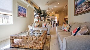 A spacious living room with a woven coffee table, a beige sofa, and a patterned rug. - Superb Naples Home w/ Den & Private Saltwater Pool (Naples)