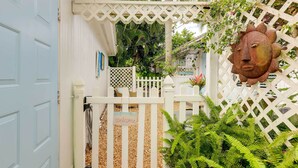 A white gate with a 'Welcome' sign, a decorative metal head, and lush green ferns. - Tropical Cottage < 2 Mi to Hobe Sound Beach! (Hobe Sound)