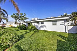 Une maison de plain-pied avec une pelouse bien entretenue, un petit jardin et une façade blanche.