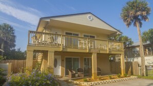 A two-story building with a balcony, a covered porch, and a sign indicating 'Sugar Palm Villa'. - Beach Villa ~ Pet Friendly ~ Fenced Yard ~ Steps to the Beach!!! (Saint Augustine)