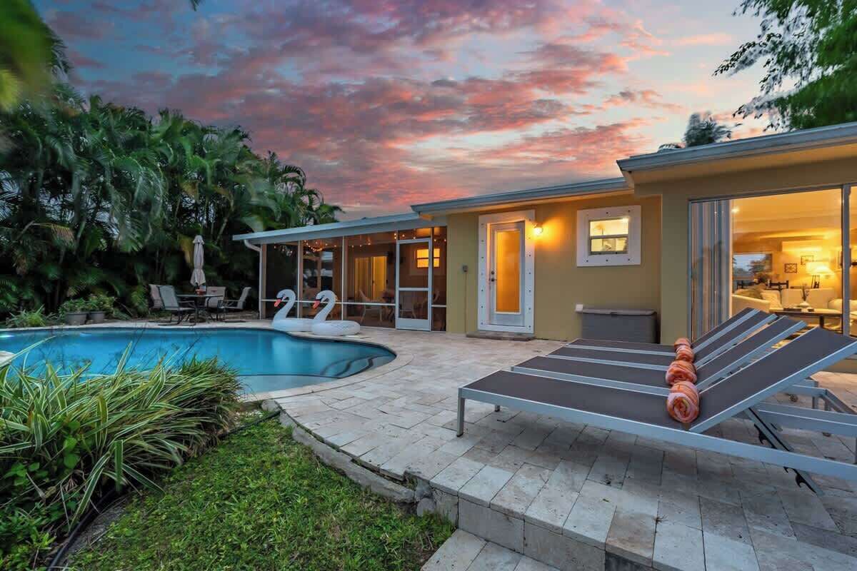 Un espace aménagé au bord de la piscine, avec des chaises longues, une piscine et un bâtiment doté de portes vitrées.