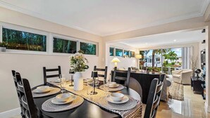 A dining area with a round table set for six, surrounded by chairs. - Waterfront 3BR Home w/ Heated Pool & Kayaks (Pompano Beach)