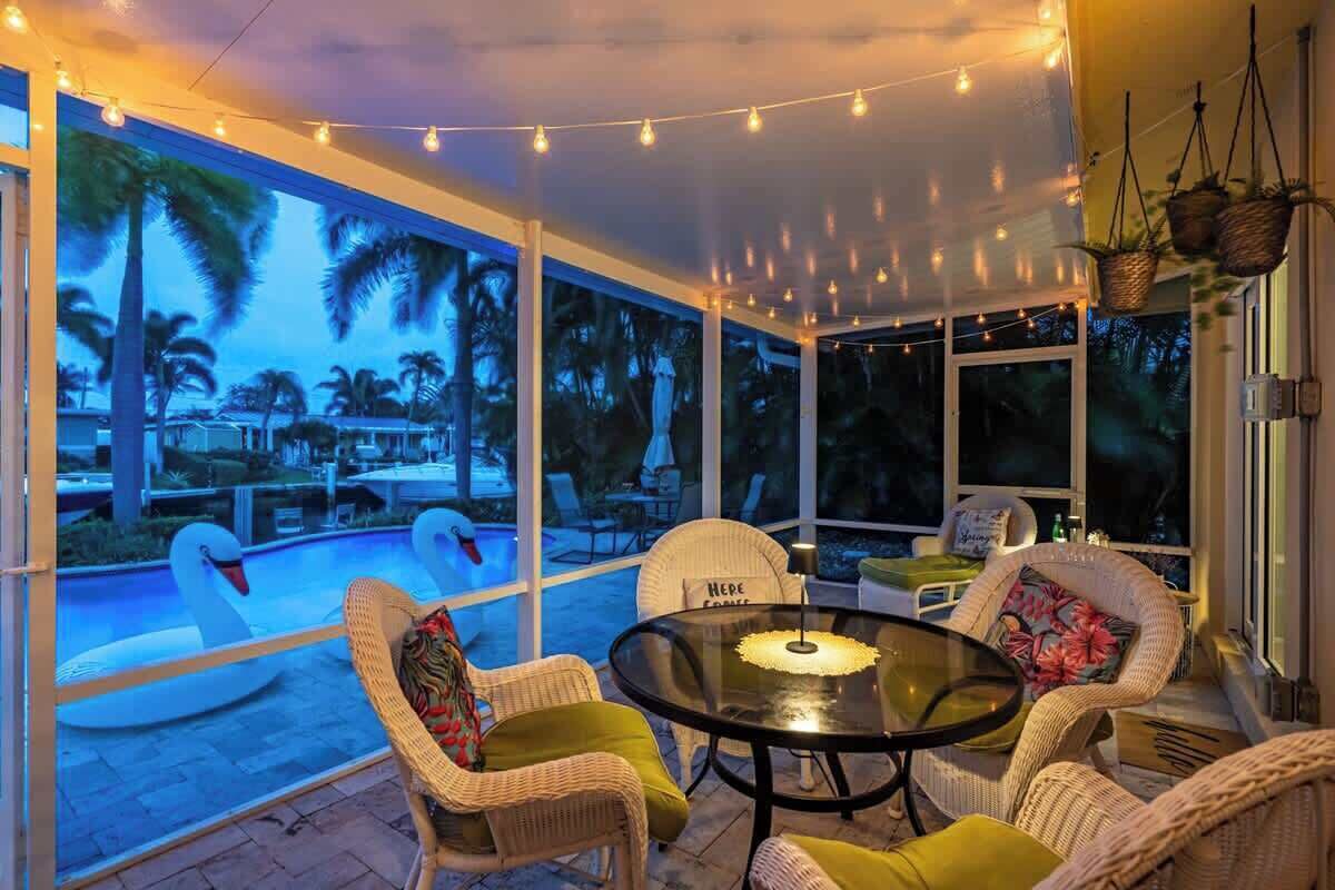 A cozy outdoor seating area with wicker chairs and a glass table, overlooking a swimming pool with swan-shaped floats.