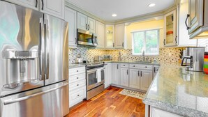 Una cocina moderna con electrodomésticos de acero inoxidable, armarios blancos y un salpicadero con diseño.
