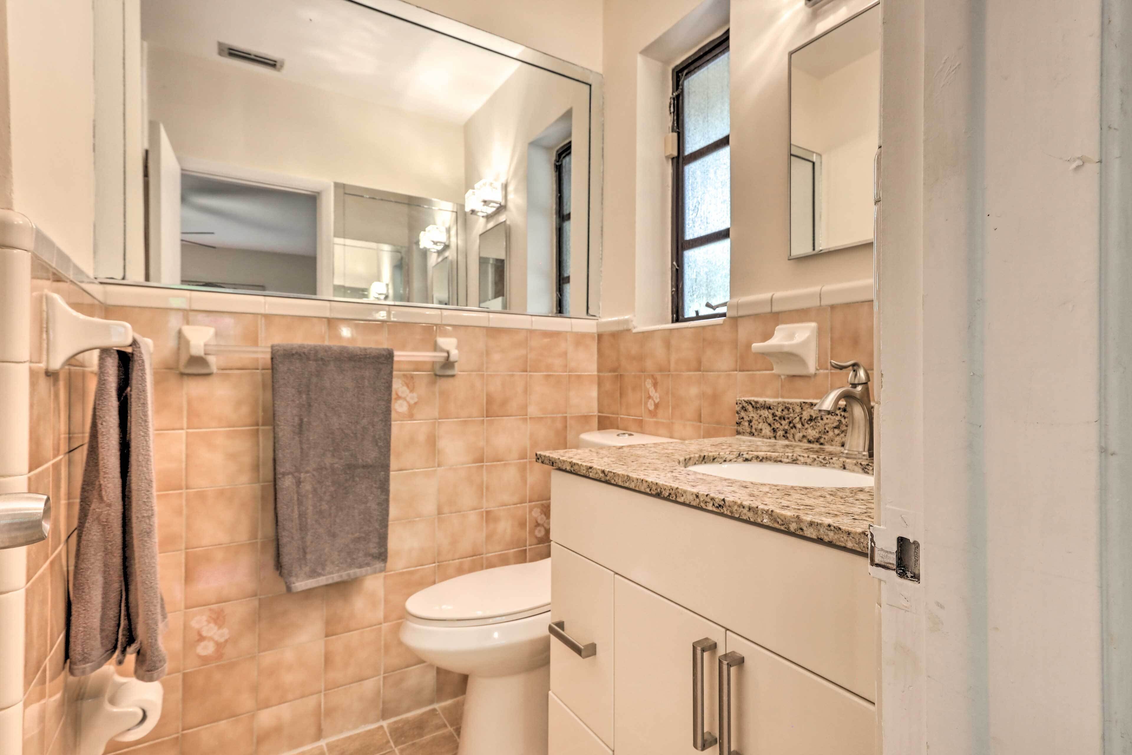 A bathroom with a toilet, sink, and mirror.