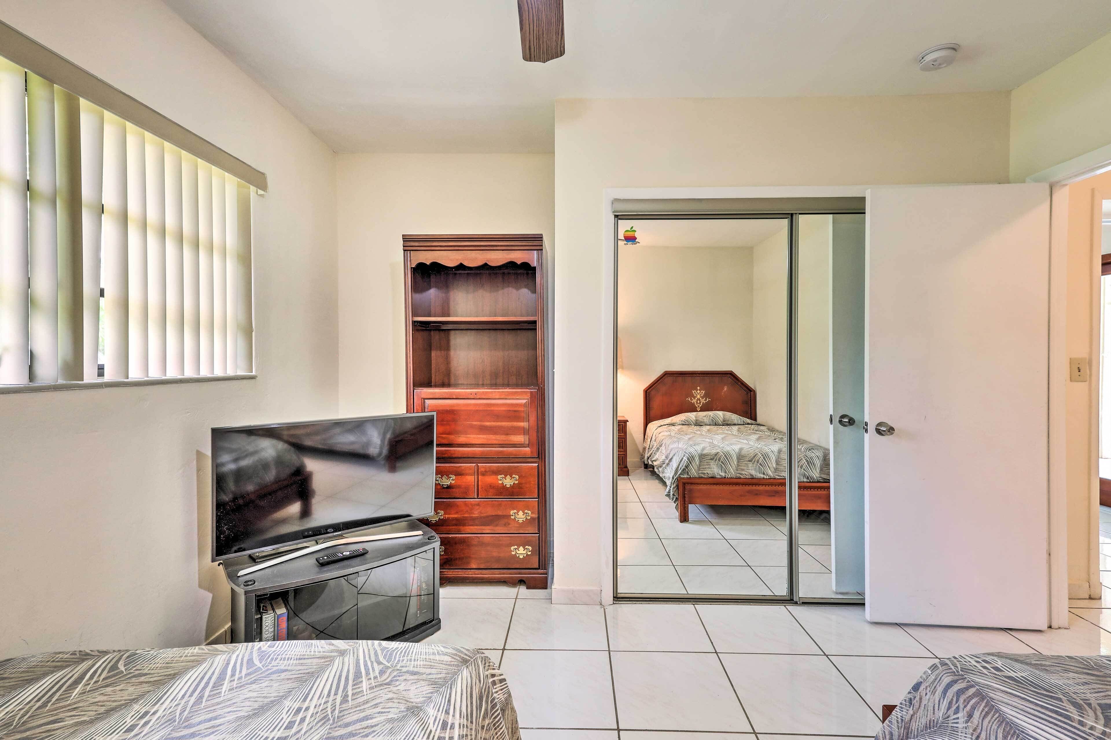 Une chambre avec une télévision, une armoire en bois et un lit.