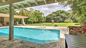 A covered swimming pool with lounge chairs and a view of a lush garden. - Home w/ Pool in Upscale Pinecrest Village (Miami)