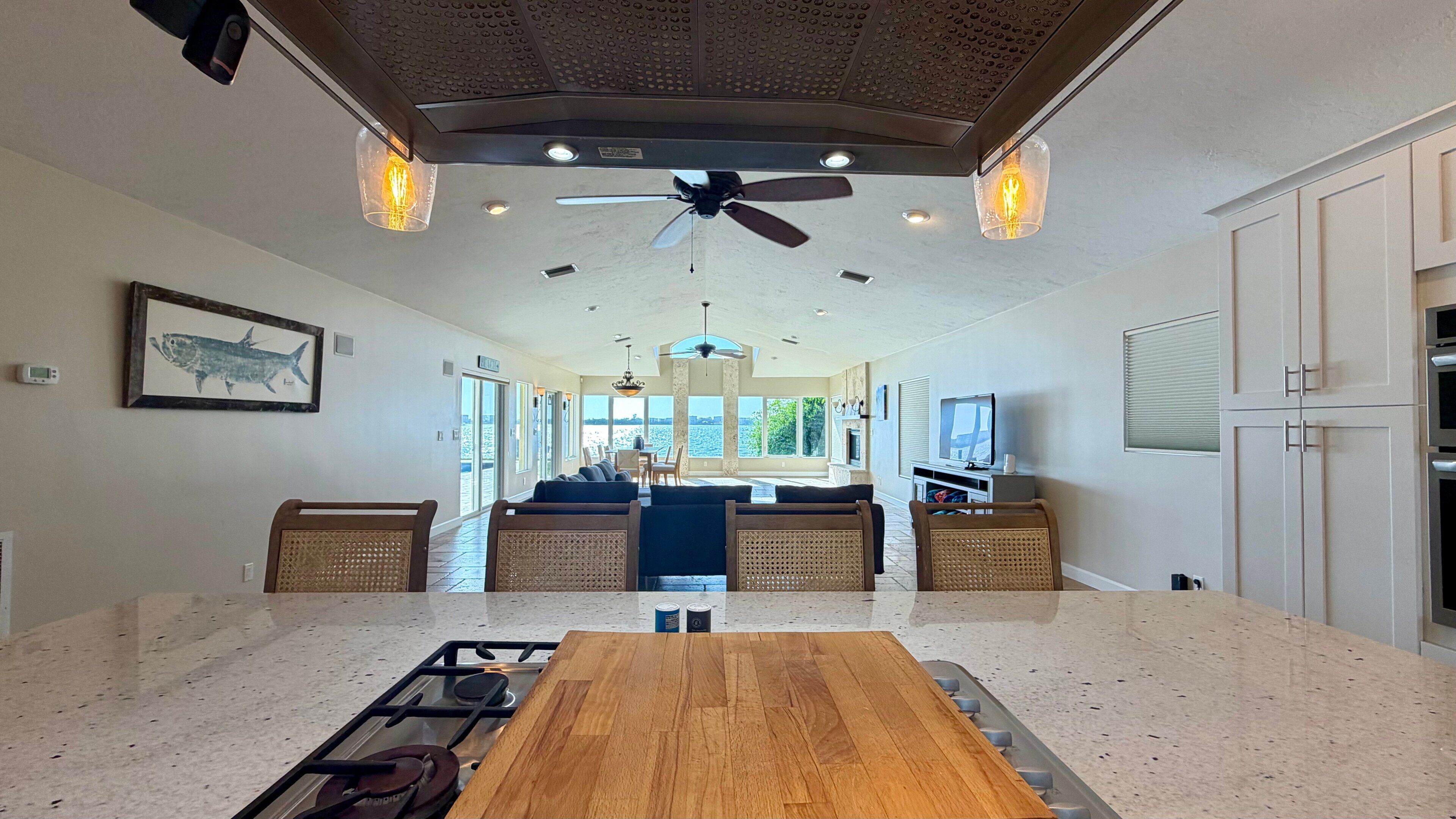 A spacious living area with a central seating arrangement, a kitchen with a gas stove, and a ceiling fan.
