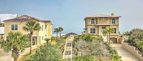 A residential area with two houses, a paved pathway, and a view of the ocean.