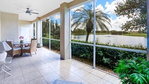 Una habitació àmplia amb grans finestres que donen vista a un llac i palmeres.