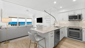 A modern kitchen with white cabinetry, a built-in oven, and a large island with bar stools.