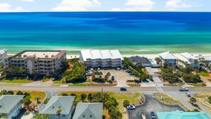 A coastal hotel with multiple buildings, a parking lot, and a view of the ocean.