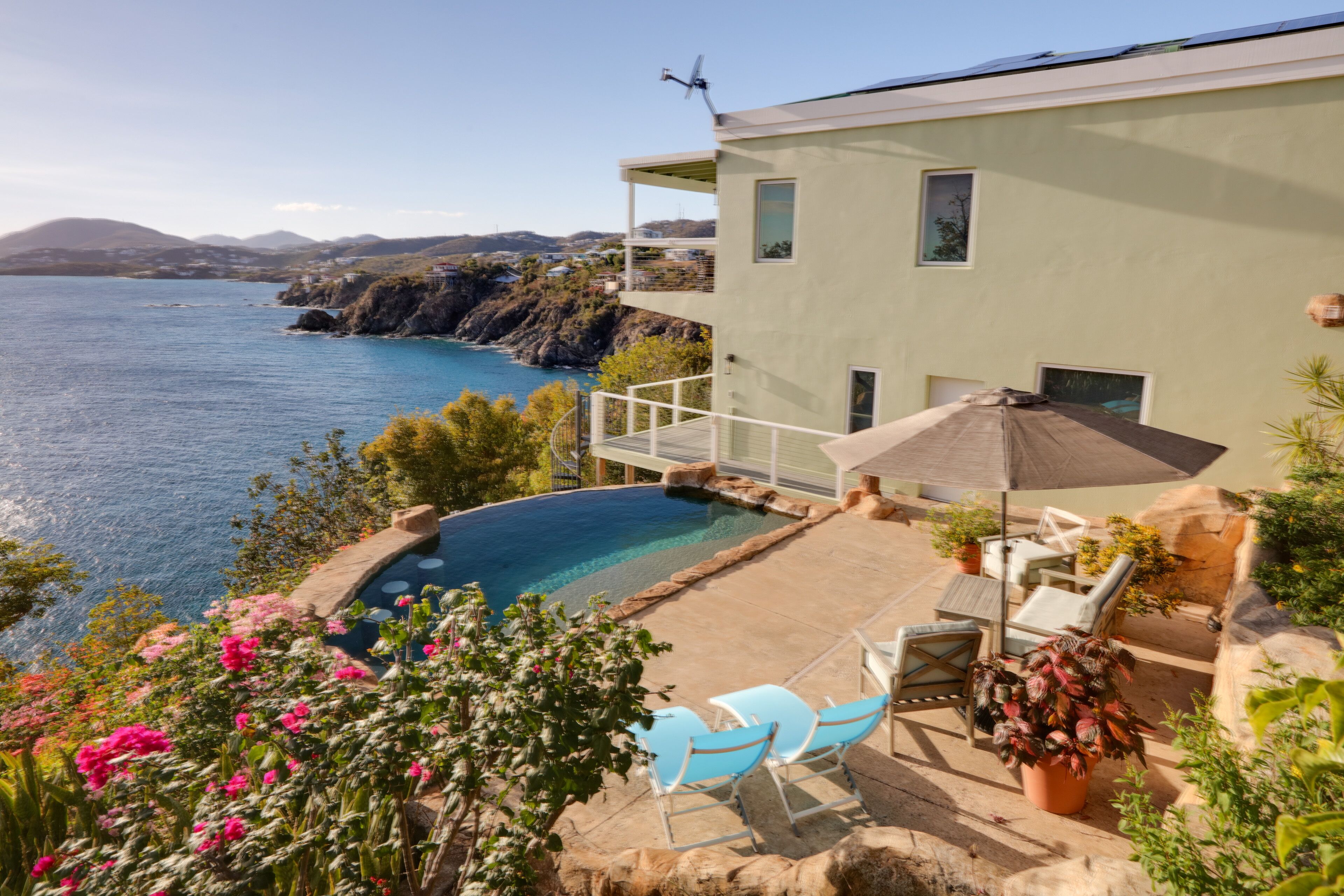 Ein modernes Haus mit Pool, Sitzgelegenheit im Freien und Meerblick.