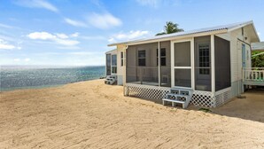 Ein Strandhaus mit überdachter Veranda, großen Fenstern und Meerblick.