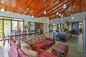 A spacious living area with a red sofa, a dining table, and a kitchen area.