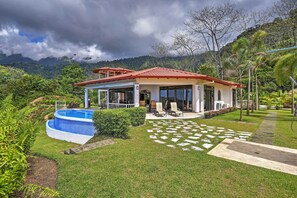 A house with a swimming pool, surrounded by lush greenery and mountains.