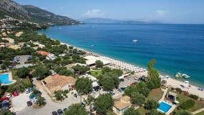 A coastal resort with a beach, swimming pool, and a view of the sea.