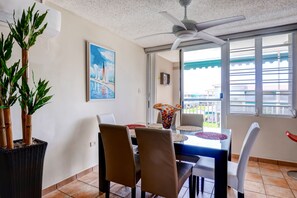 Un espace repas comprenant une table, des chaises, un ventilateur de plafond et des plantes en pot.