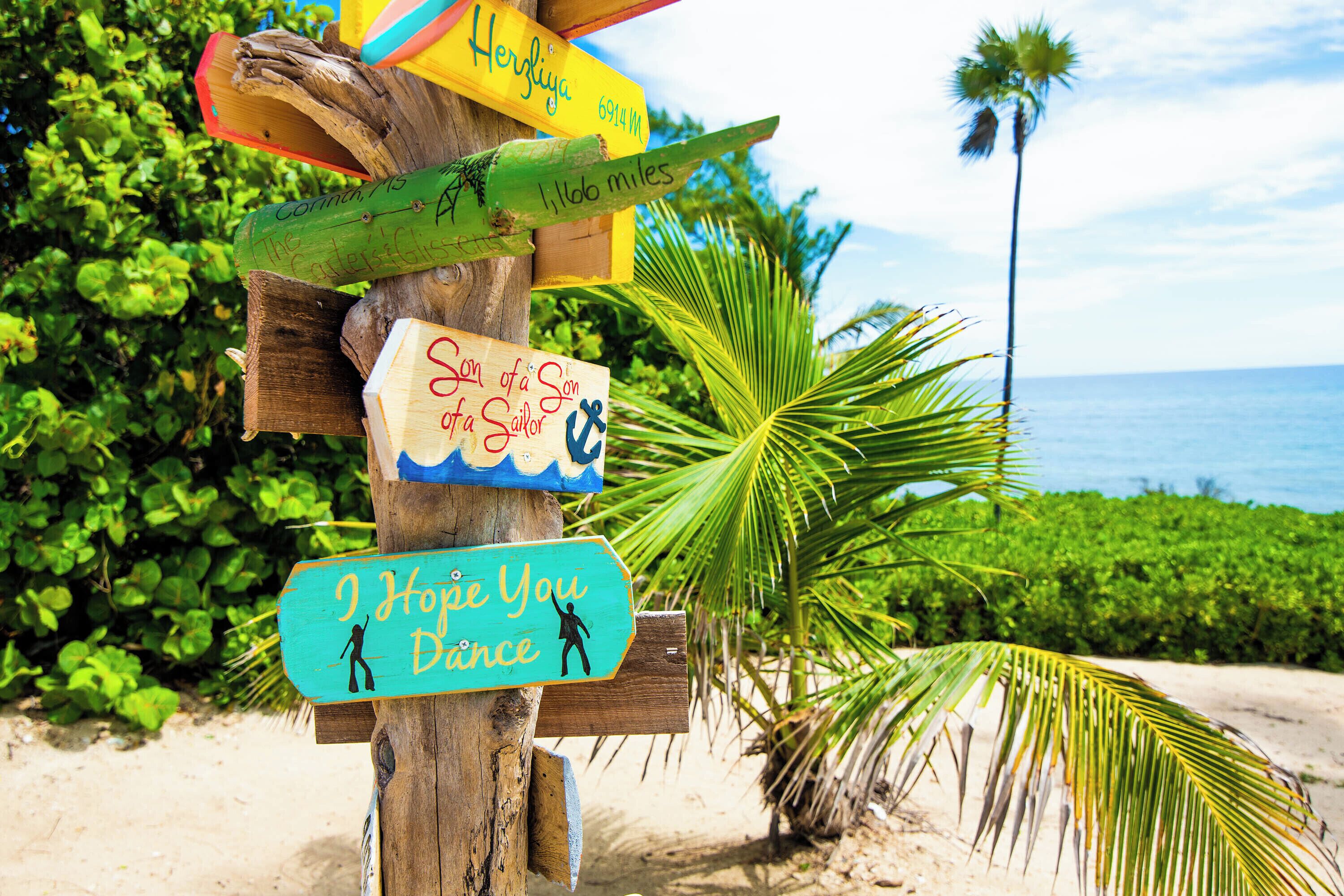 A wooden signpost with multiple directional signs, including one that says "Son of a Sailor."
