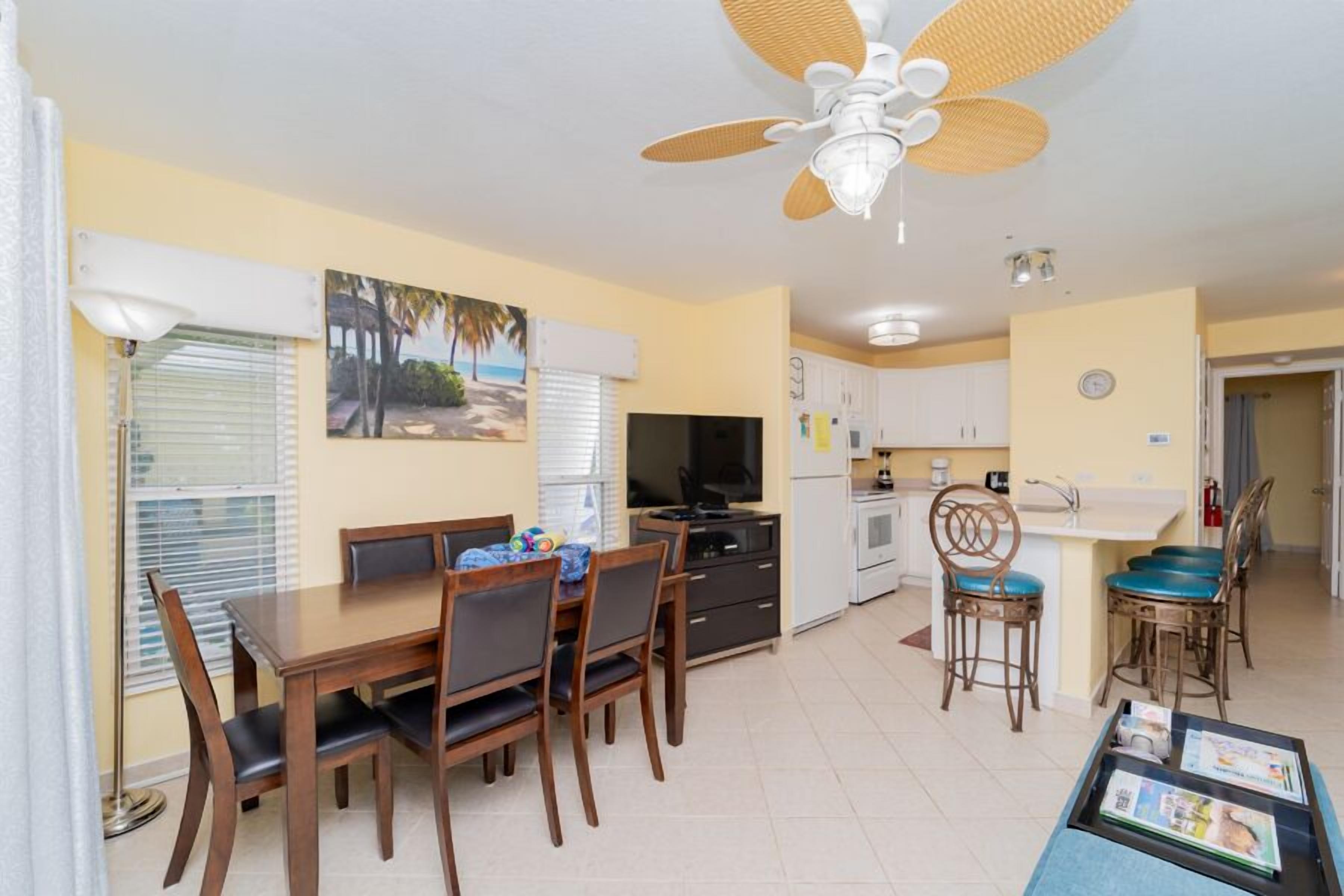 Un espace de vie compact comprenant un coin repas, une kitchenette et un ventilateur de plafond.