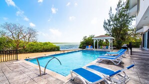 A pool area with lounge chairs and a gazebo overlooking a body of water. - Hidden Cove: Family Hideaway w/Free Kayaks & Bikes, Private Pool and Dock (Cayman Kai)