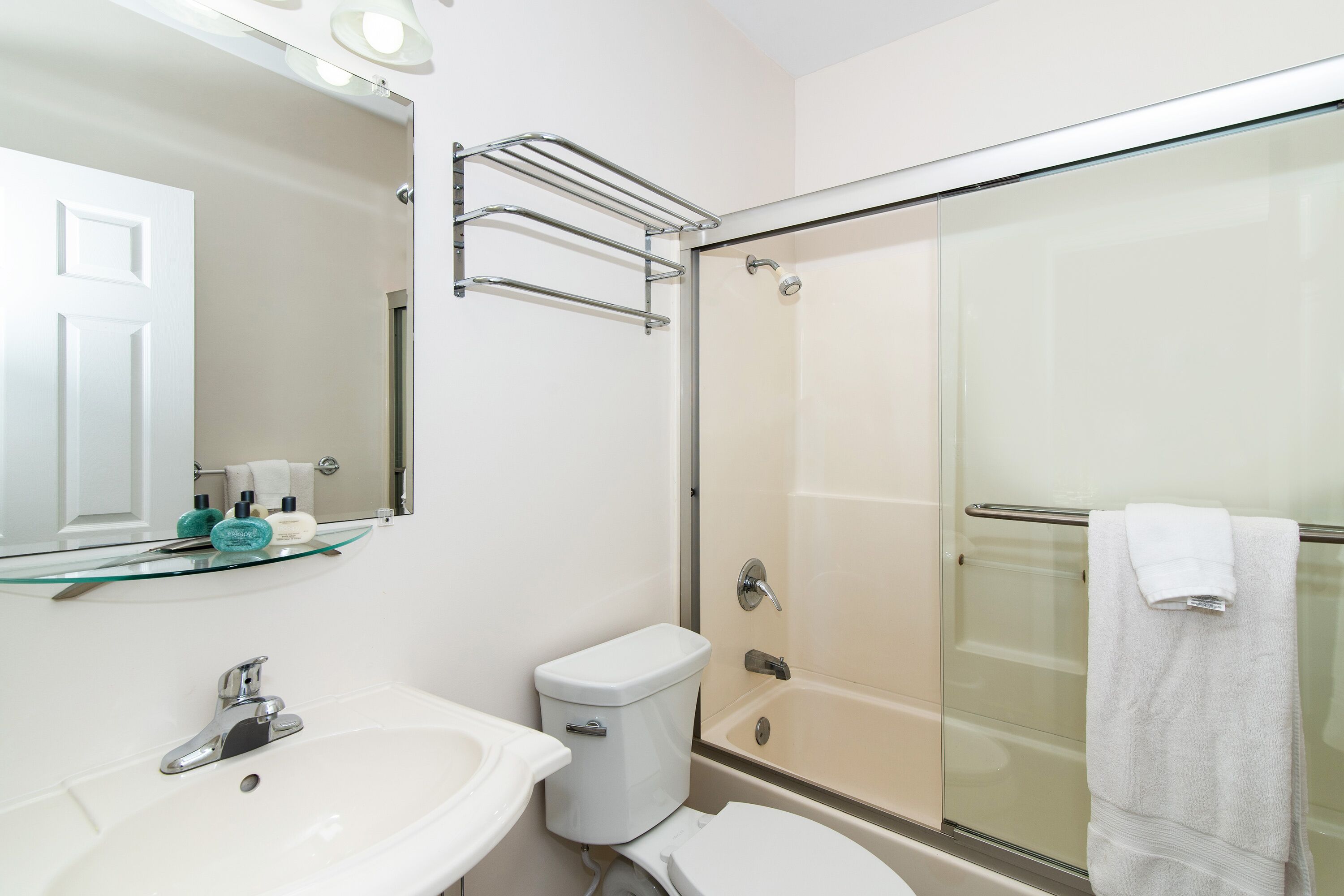 Un baño con cabina de ducha de vidrio, un lavamanos blanco y un inodoro.