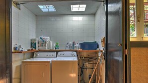 A laundry room with a washing machine, dryer, and stacked laundry supplies. - Tropical Ponce Home: Private Pool & Outdoor Oasis! (Ponce)