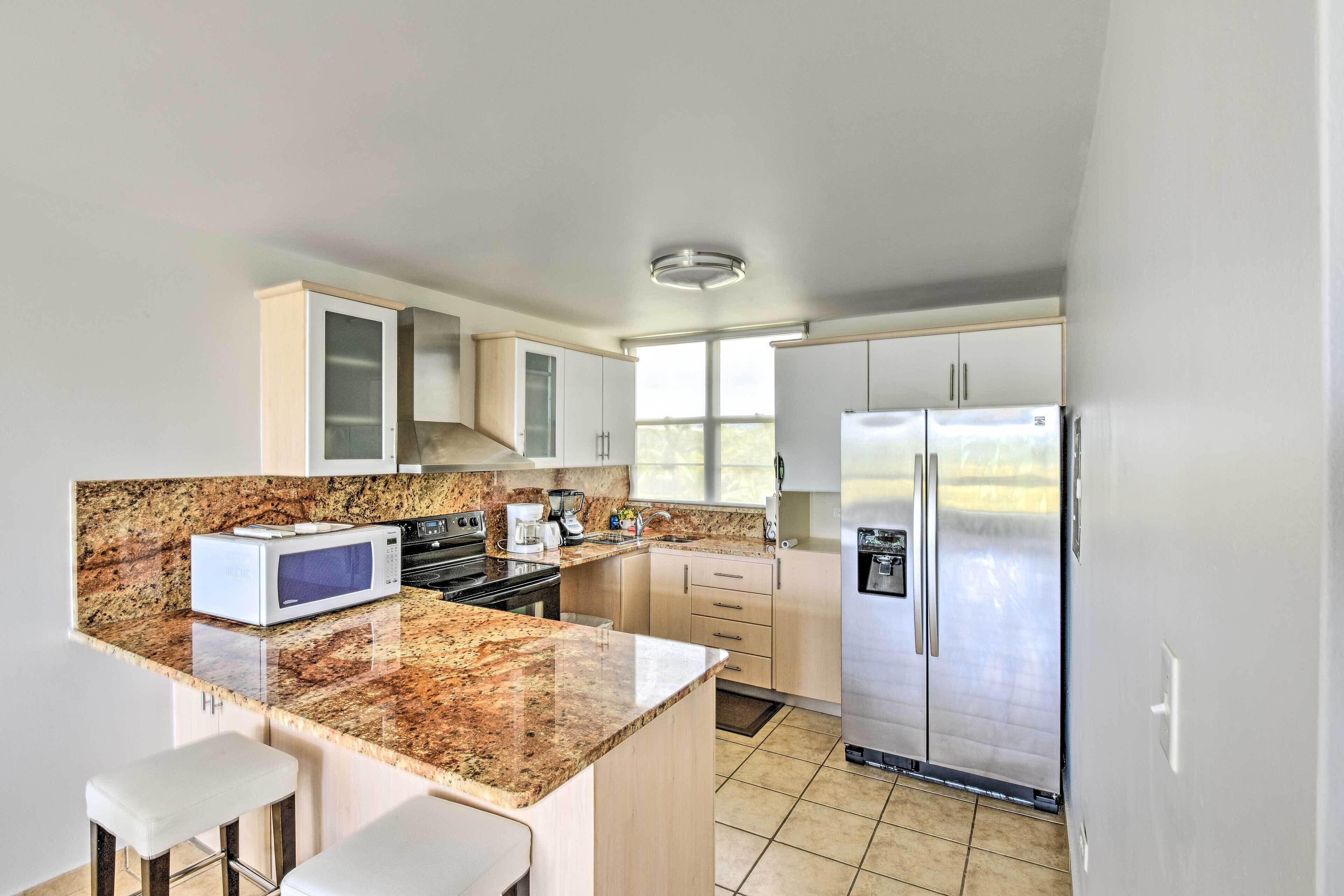 A modern kitchen with granite countertops, stainless steel appliances, and a built-in island with bar stools.
