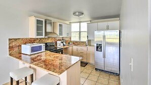 Eine moderne Küche mit Granit-Arbeitsplatten, Edelstahlgeräten und einer integrierten Kochinsel mit Barhocker.