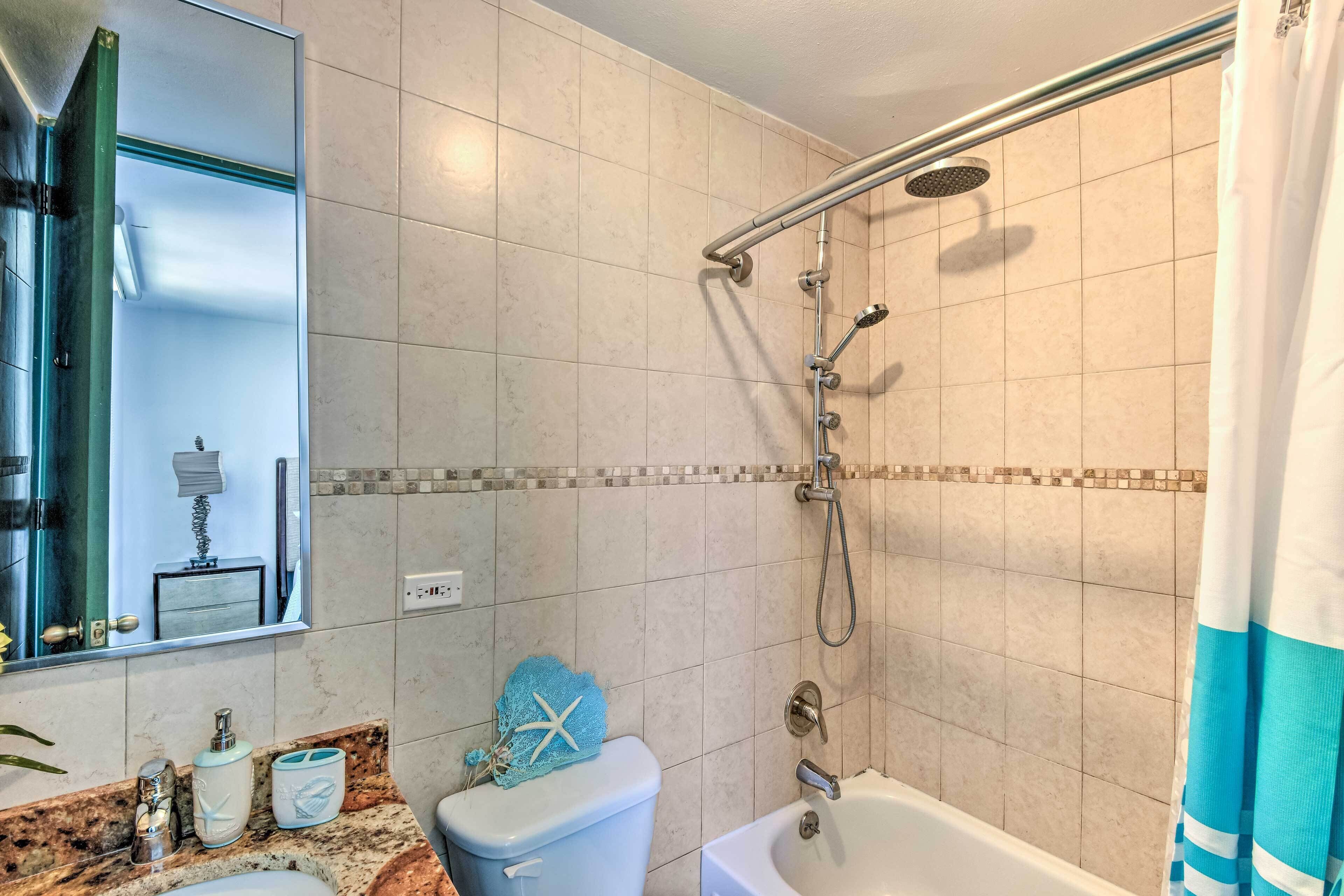 Ein Badezimmer mit Dusche, Toilette, Waschbecken und Spiegel.