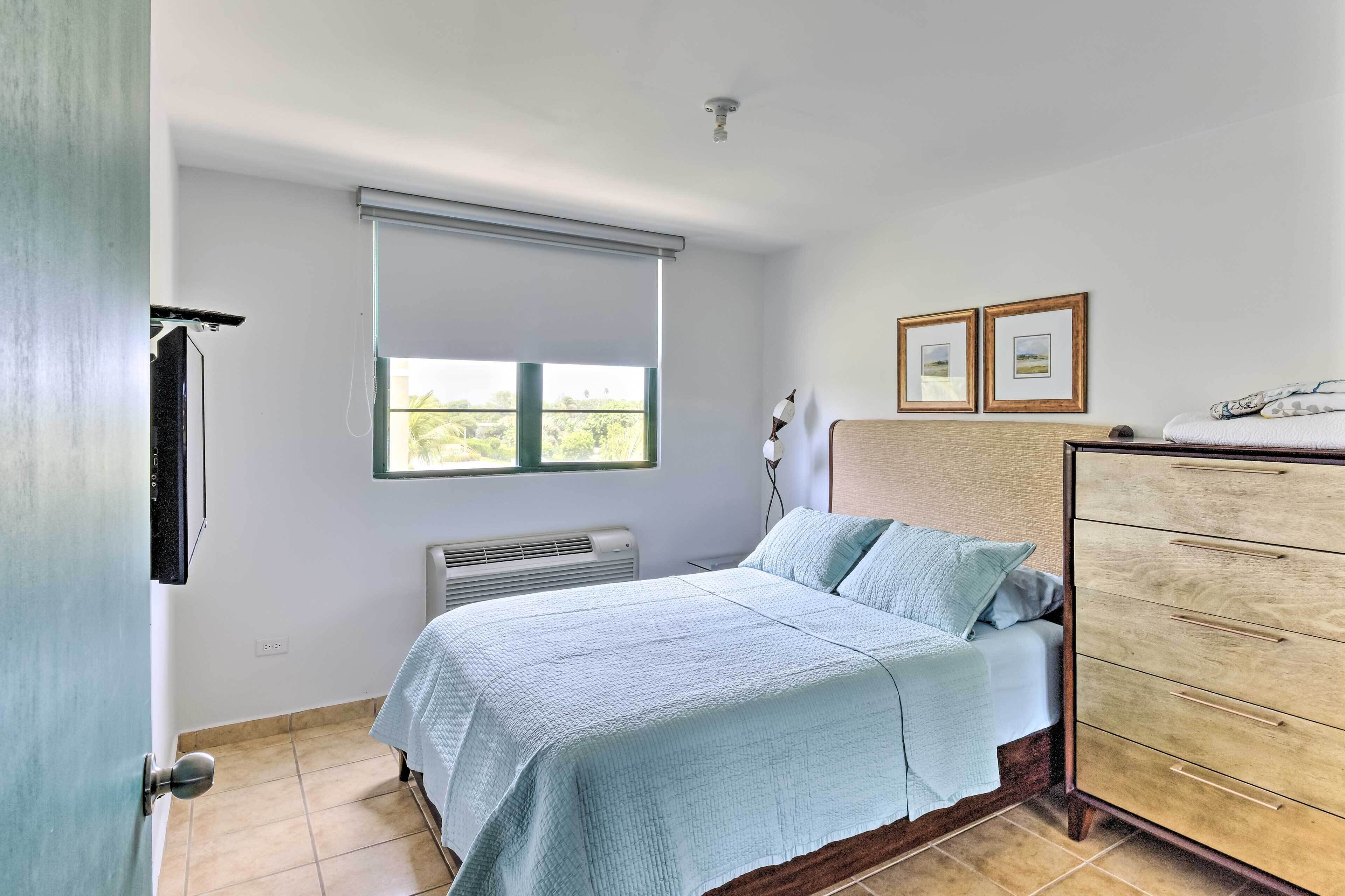 A bedroom with a bed, a dresser, a window with blinds, and a radiator.