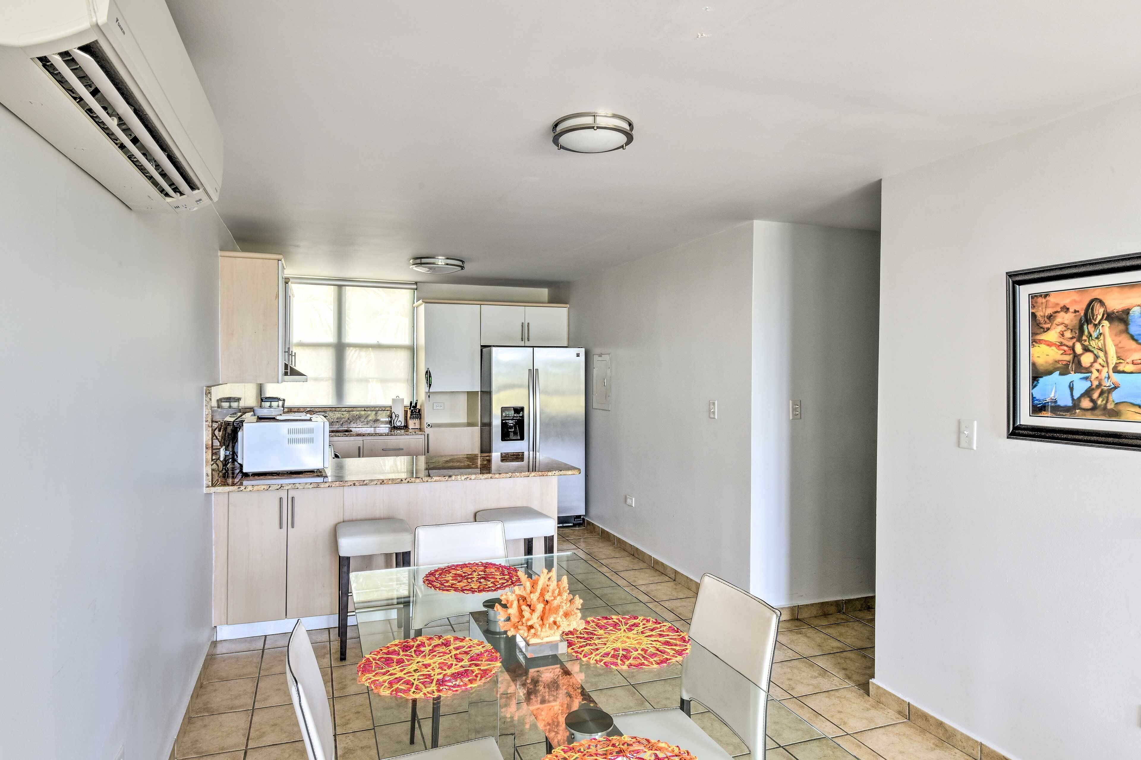 A modern kitchen with a dining area, featuring a refrigerator, stove, and a dining table with chairs.