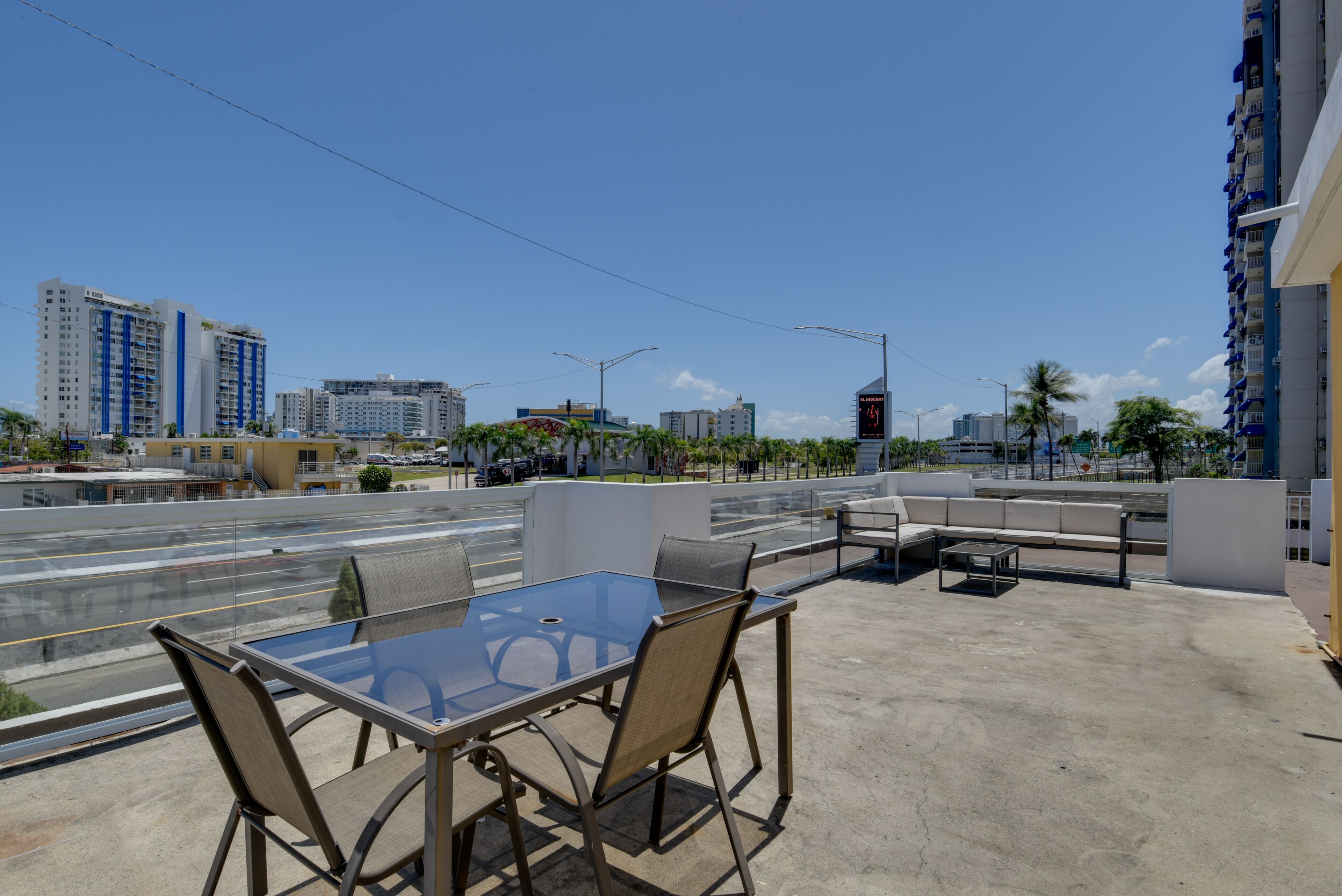Une terrasse extérieure avec une table et des chaises en verre, un canapé et une petite table.