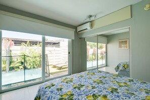 Un dormitorio con una cama grande, una puerta corrediza al balcón y vista a una piscina.