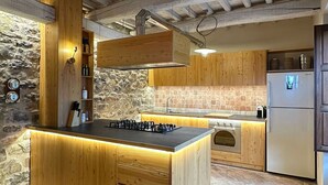 Una cocina con armarios de madera, una pared de piedra, una estufa empotrada y un refrigerador.