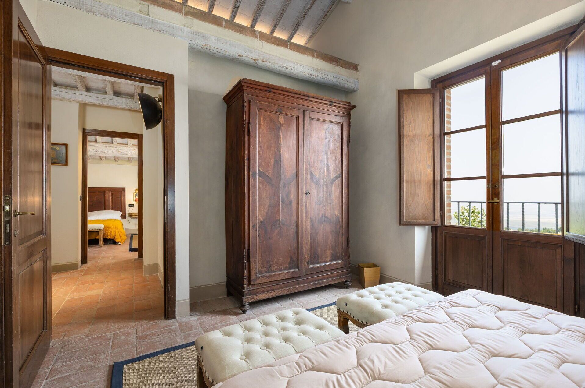 Un dormitorio con un armario grande, una cama con cabecero tapizado y una ventana con vistas.