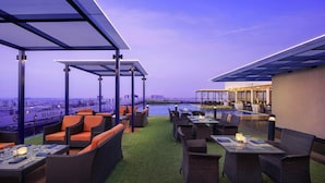 An outdoor terrace with seating and tables, overlooking a body of water and cityscape. - Marriott Executive Apartments Hyderabad (Hyderabad)