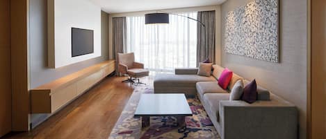 A modern living room with a flat-screen TV, a sofa, a coffee table, and a patterned rug.
