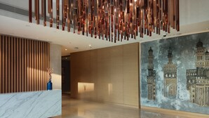 A modern lobby with a marble reception desk, a vertical light installation, and a wall mural of Islamic architecture. - Marriott Executive Apartments Hyderabad (Hyderabad)
