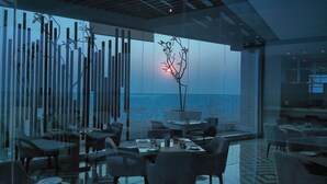 A modern restaurant with a glass facade, contemporary furniture, and a central decorative tree. - Marriott Executive Apartments Hyderabad (Hyderabad)