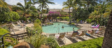 A pool area with lounge chairs, palm trees, and a building in the background.