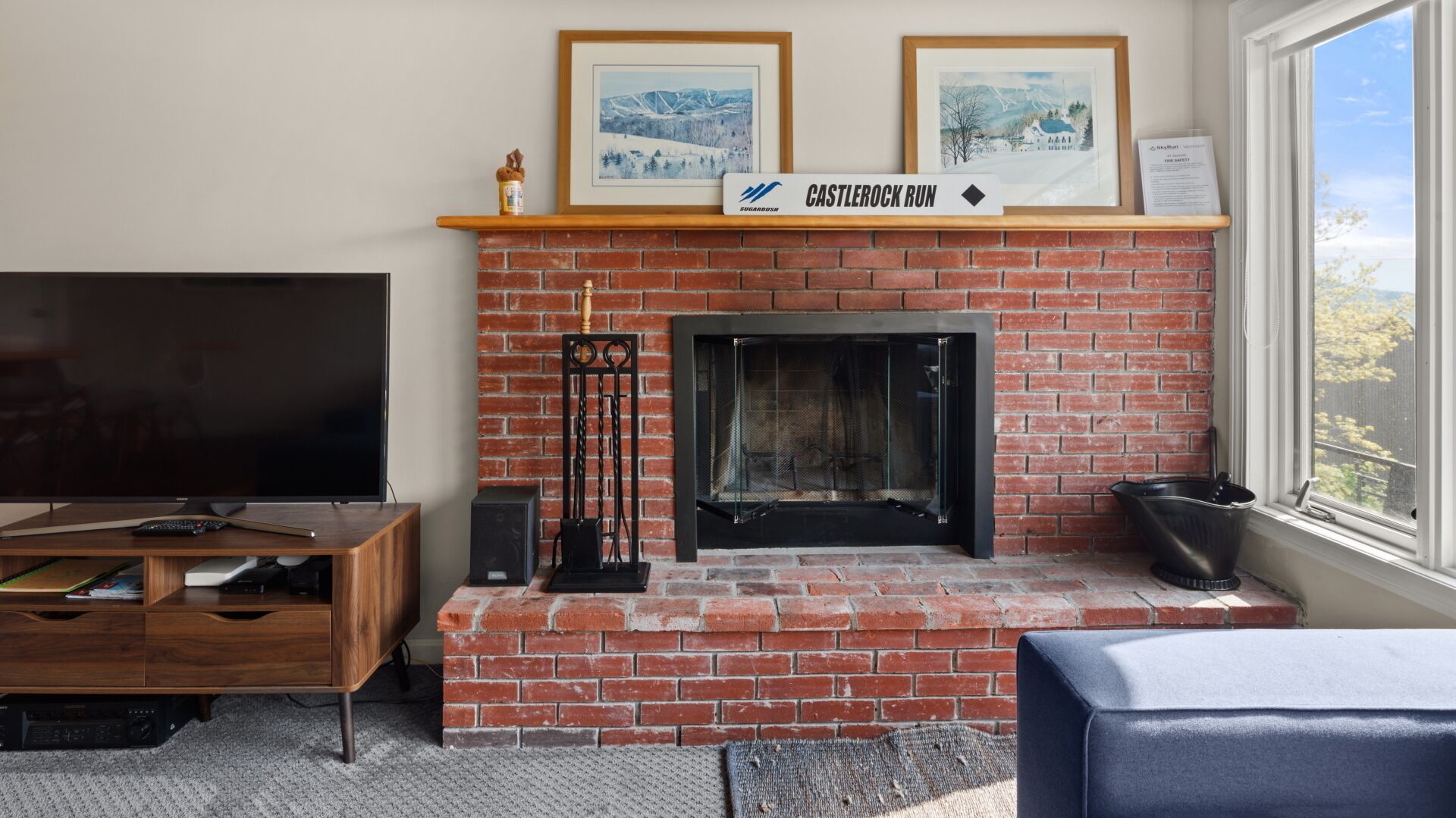 A living room with a brick fireplace, a television, and a sign that reads "CASTLE ROCK RUN".