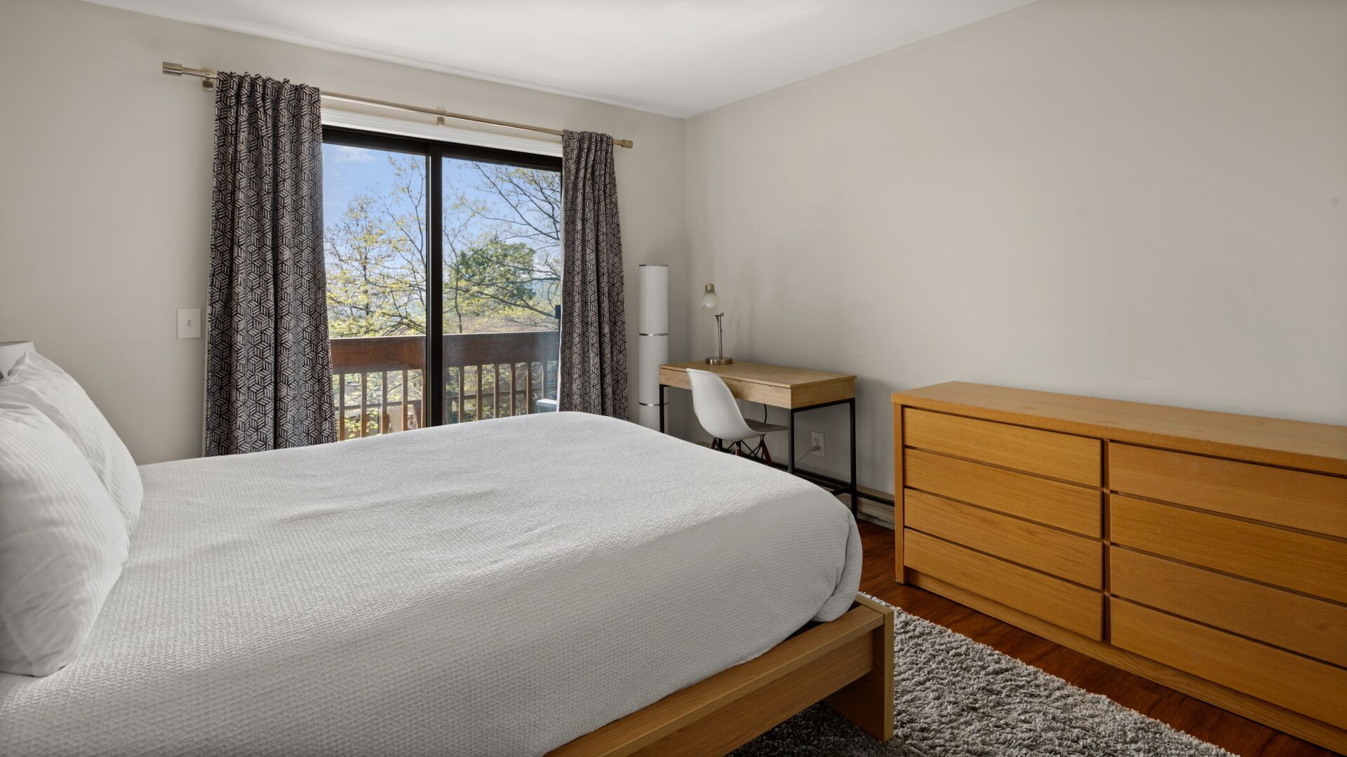 A bedroom with a bed, a desk, and a dresser.