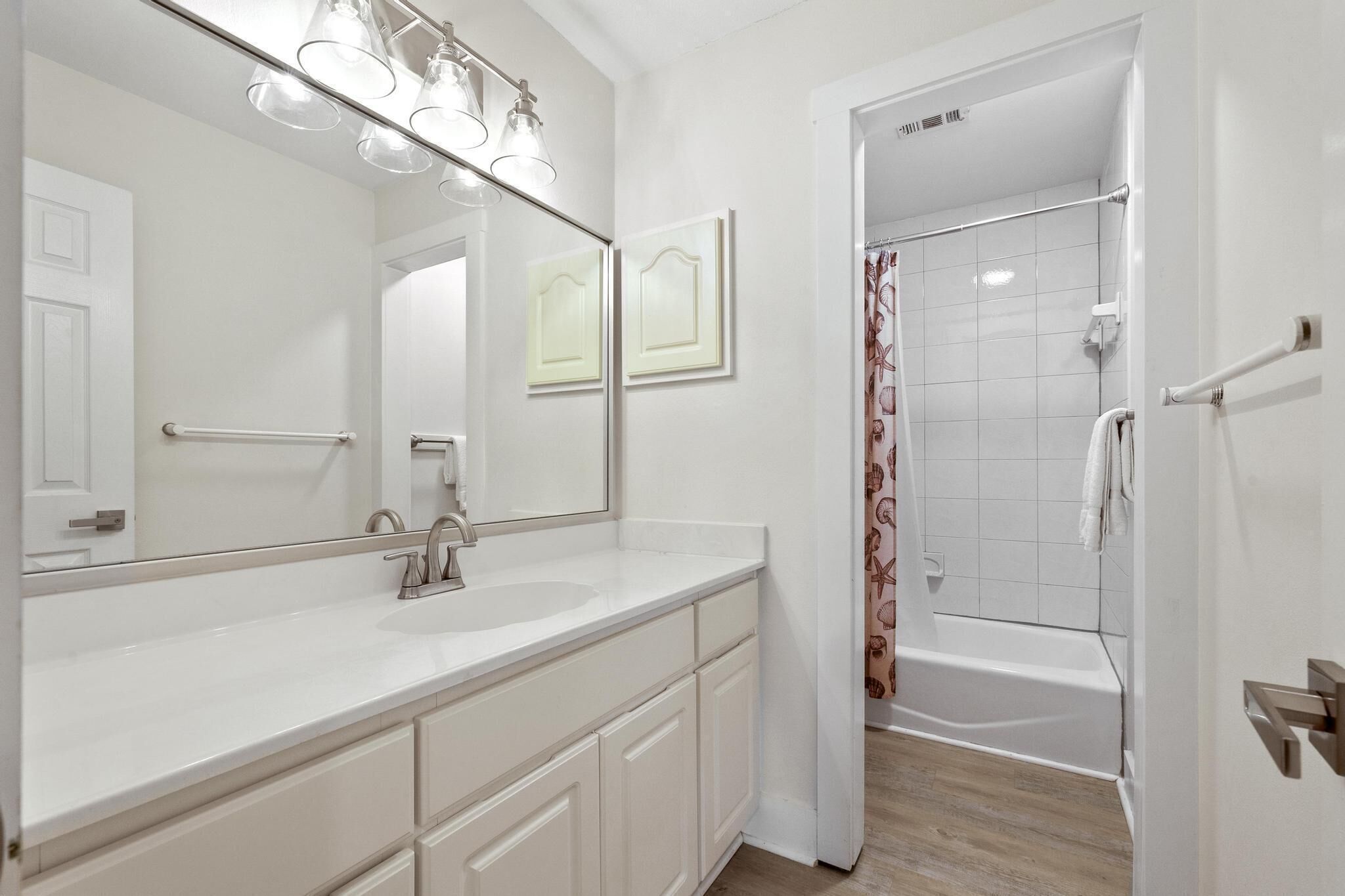 A bathroom with a white vanity, a large mirror, and a shower area with a glass door.