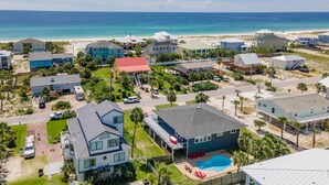 A coastal residential area with houses, a swimming pool, and a beach in the background. - Gorgeous Gulf View Home with Private Pool! Pet friendly too! (Pensacola Beach)