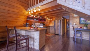 Ein Holzblockbau-Innenraum mit Küche, Essbereich und einer Treppe.