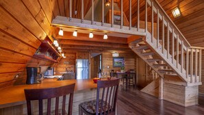 Ein gemütliches Blockhaus-Interieur mit einer Holztreppe, einer Küchenzeile und einem Essbereich.