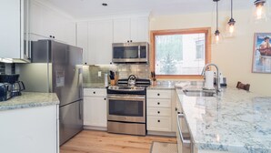 Een moderne keuken met roestvrijstalen apparatuur, witte kasten en een marmeren aanrecht.