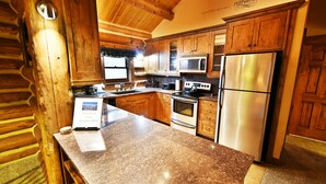 Une cuisine dotée de meubles en bois, de plans de travail en granit, d’appareils électroménagers en acier inoxydable et d’une enseigne accueillant les visiteurs à Chase Meadows West.