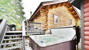 Une cabane en rondins avec un jacuzzi et une terrasse.